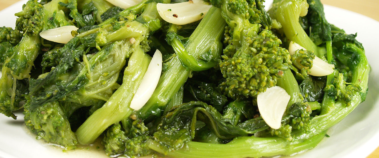 Broccoli rabe with tender stems, leafy greens, sliced garlic, olive oil, and seasonings.
