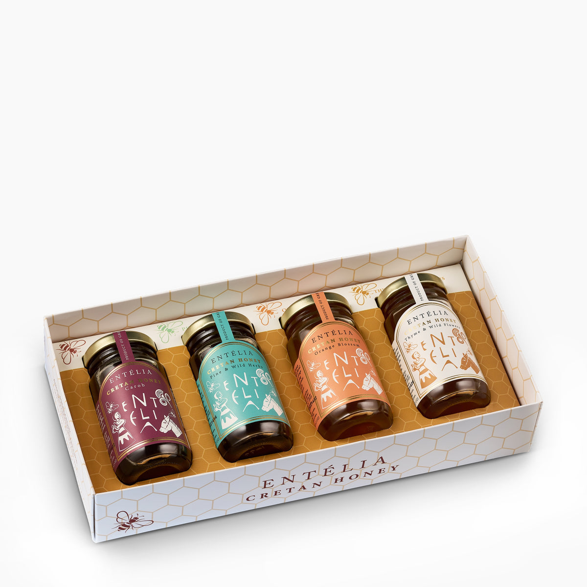 Angled view of an open Entelia gift box containing four 100 g jars of Cretan honey.