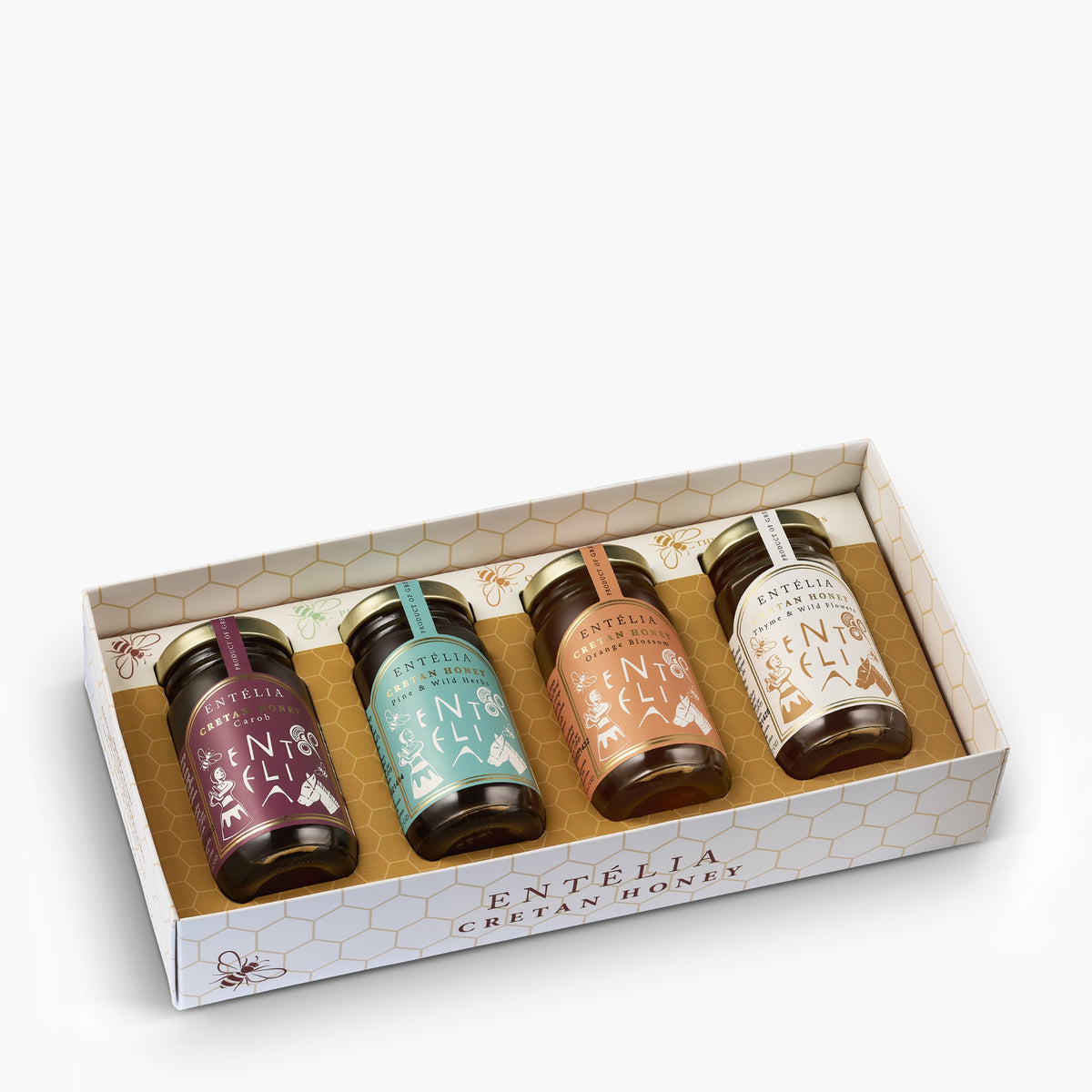 Angled view of an open Entelia gift box containing four 100 g jars of Cretan honey.