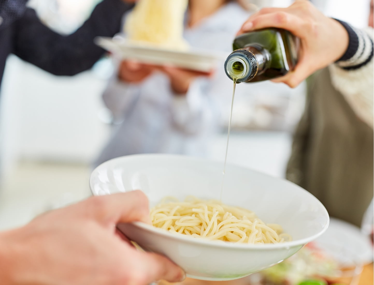 olive oil pouring on pasta