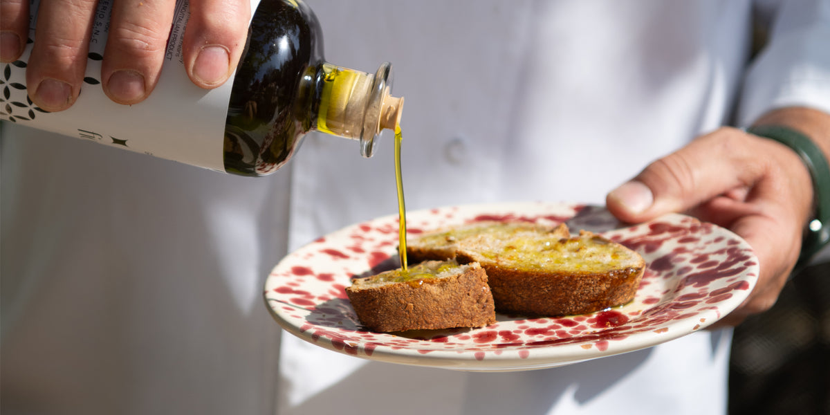 A chef pouring high-quality extra-virgin olive oil over freshly baked bread.